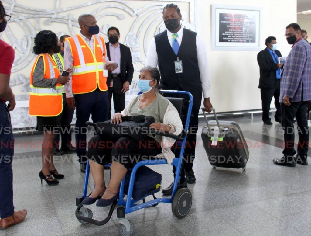 Passenger Pamela Ramnath is assisted by passenger service agent Tyrell Da Costa after she returned from Guyana at the Piarco International Airport when international flights resumed on Saturday.  - Photo by Ayanna Kinsale