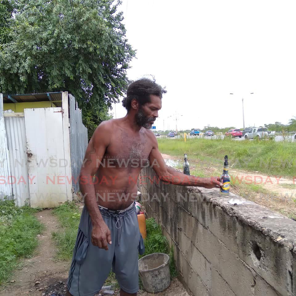 Beetham resident Elvis Riley fixes a makeshift torch on a wall after Kevin Thompson, 4, was killed when trying to cross the Beetham Highway with his mother and brother on Friday night.  - Photo by Shane Superville