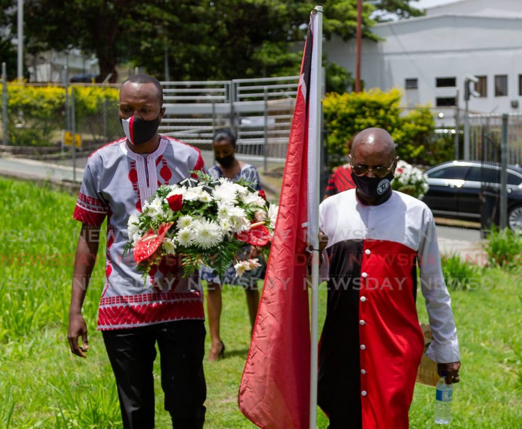 Chief Secretary Ancil Dennis, left, walks alongside ex-hostage Wendell Eversley towards the grave of former Prime Minister ANR Robinson in Bacolet on Friday, to lay wreaths in recognition of those who suffered as a result of the 1990 attempted coup.  - DAVID REID 