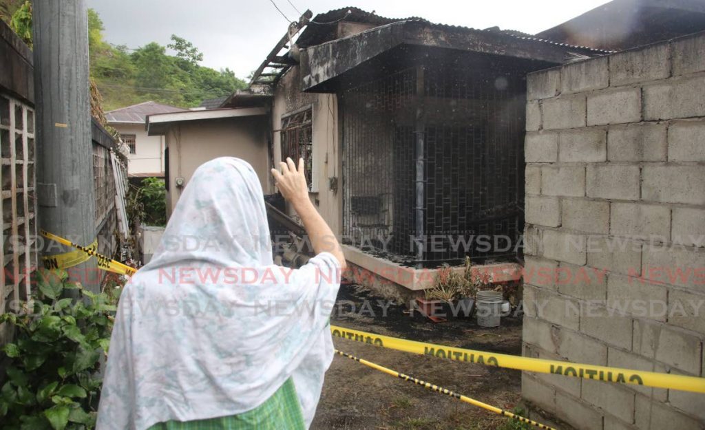 An old man offers a Mahikari  prayer that he said helps the souls that perish in tragedy outside the remains of a burnt home at No 1 Rookery Nook, Maraval, Tuesday. Three children aged 17, six and three perished in a blaze at the home on Monday morning. - SUREASH CHOLAI