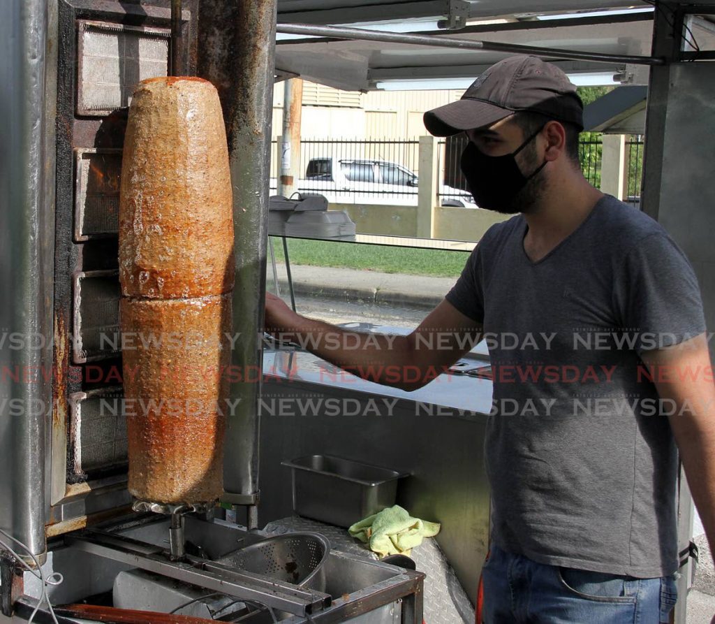 Hisham Zahareddin turns the heat up on meat for gyro dishes at his food truck, Cross Crossing, San Fernando on Tuesday.   - Photo by Angelo Marcelle