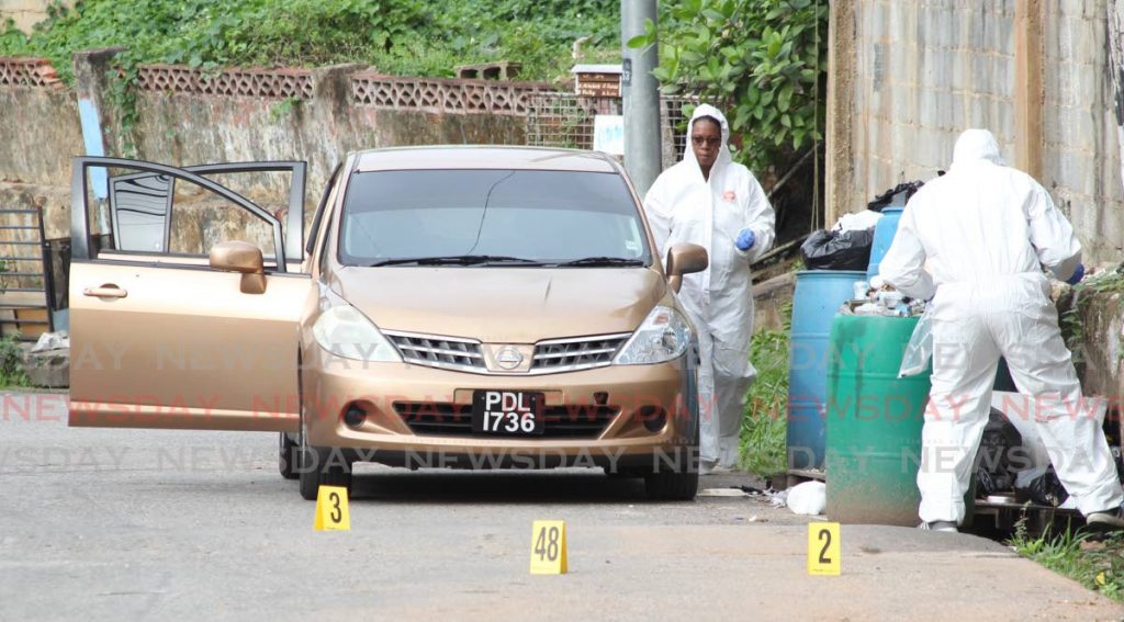 In this June 27, 2020 file photo, crime scene investigators process the area where Joel Jacobs, Noel Diamond and Israel Moses Clinton were killed by police in Second Caledonia, Morvant. - 