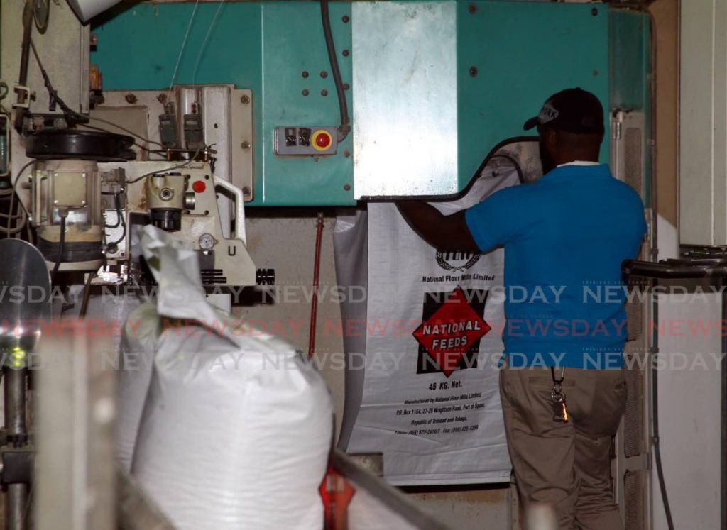 An employee fills a bag of feed at National Flour Mills (NFM) in Port of Spain. NFM is one of the companies in which National Enterprises Ltd is a shareholder. File photo/Roger Jacob - 