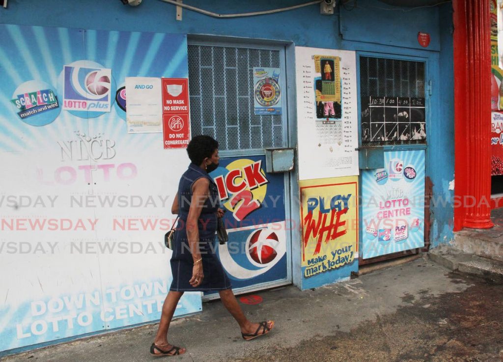 A woman walks past a closed NLCB booth on Mucurapo Road, San Fernando on May 17. NLCB booths will reopen once more on August 9. - Photo by Angelo Marcelle