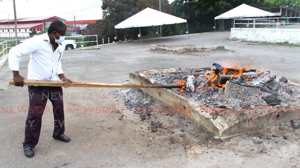 A funeral home worker attends to a pyre at the Shore of Peace cremation site in May. - Angelo Marcelle