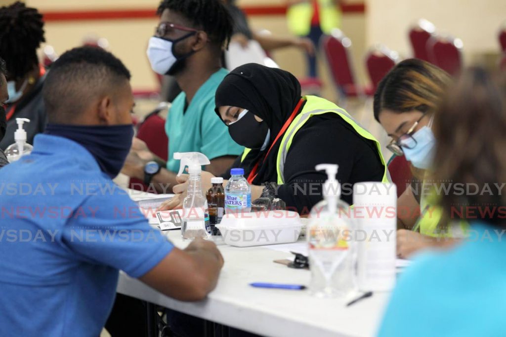 Volunteers register employees in the supermarket sector for the covid19 vaccine at Centre Pointe Mall, Chaguanas, a vaccination site managed by the Supermarkets Association. File photo - 
