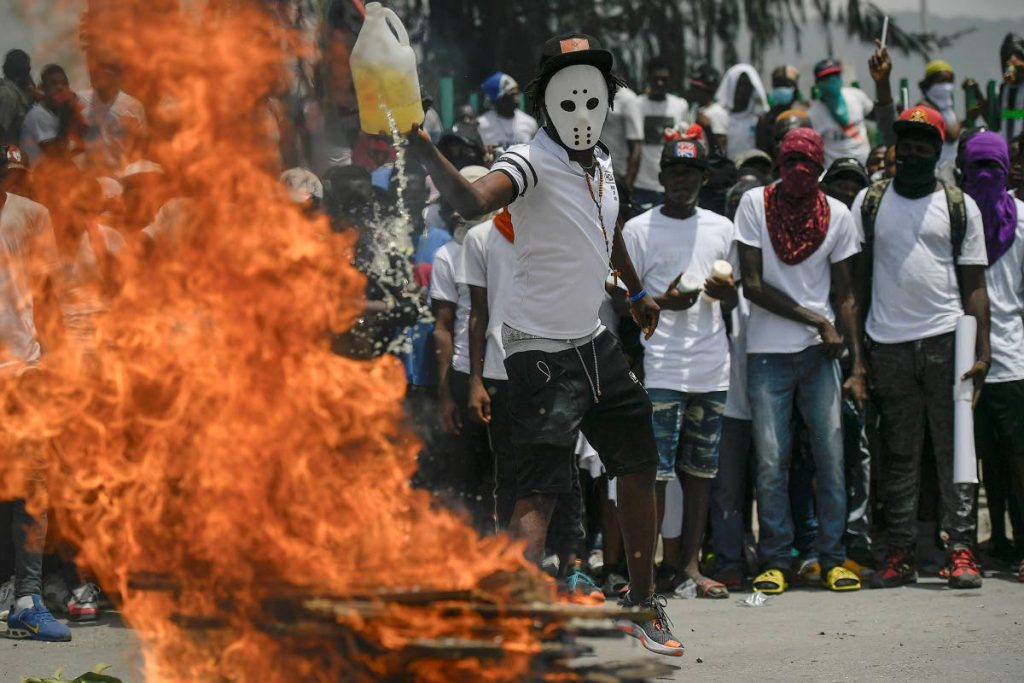 STREETS OF RAGE: A masked man ads fuel to a burning barricade on a street as members of the G9 Family and Allies, march to demand justice for slain Haitian President Jovenel Moise in La Saline neighborhood of Port-au-Prince, Haiti on July 26. AP PHOTO  - 