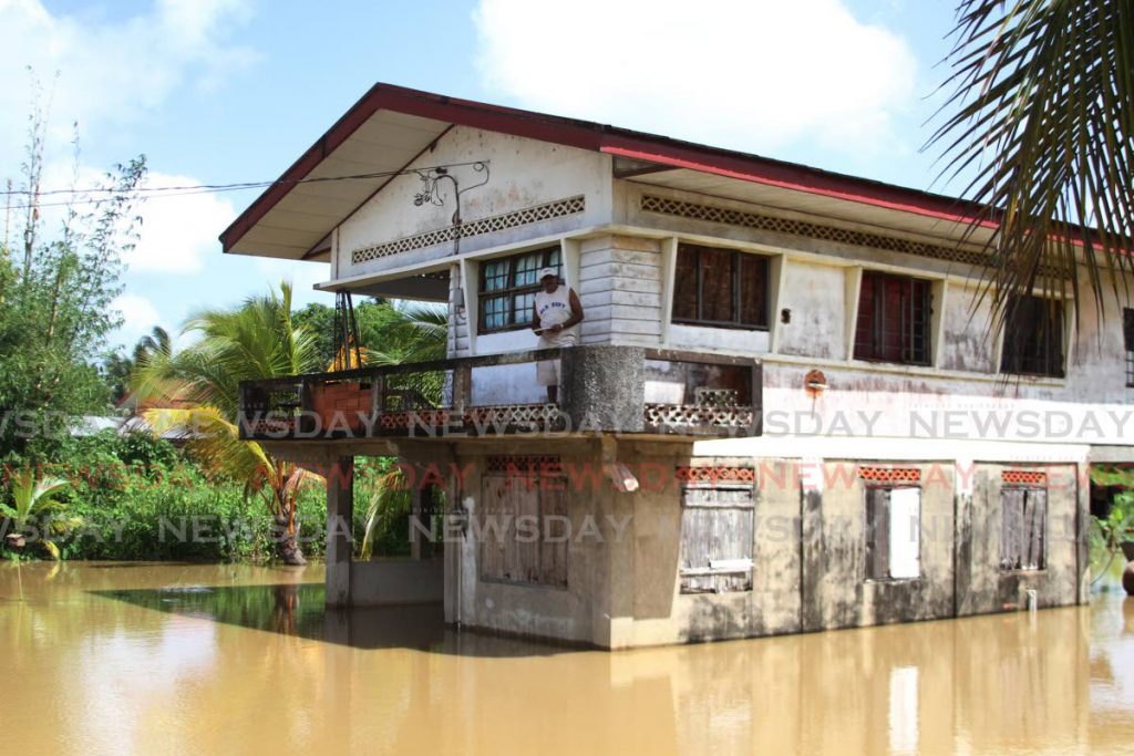 A resident is trapped in his home by floodwaters on Friday after heavy rainfall the night before. He and other residents spent their Emancipation Day weekend cleaning up in the aftermath of the floods. - Photo by Marvin Hamilton