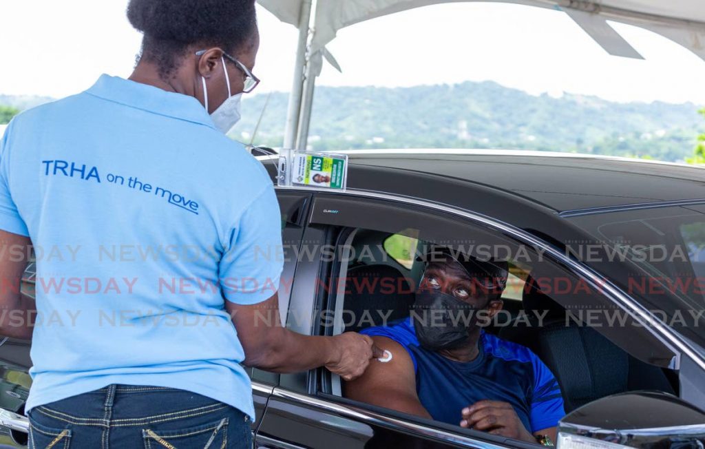  Frankie James receives his first Sinopharm jab from nurse Denise Nelson at the drive-through vaccination site in Shaw Park, Tobago on Saturday. - Photo by David Reid