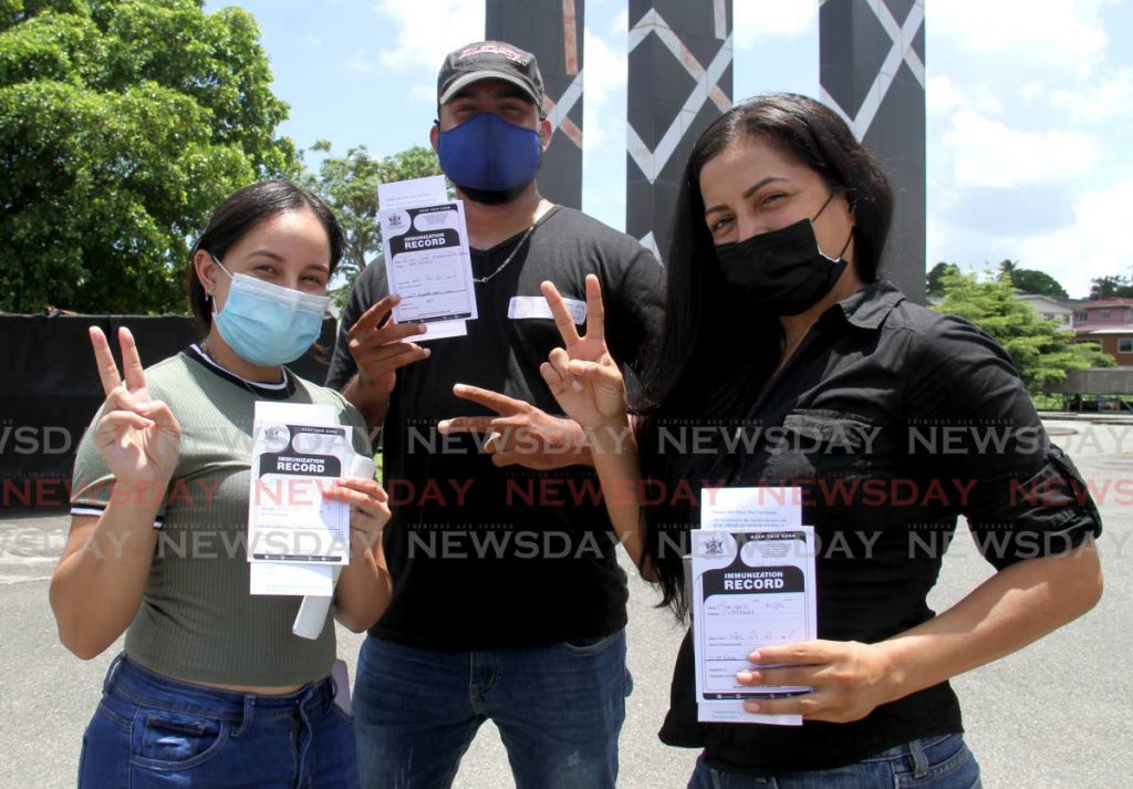 Venezuelans Kinverlins Mata, from left, Victor Handinette and Maryoris Rojas displays their vaccination cards and the vaccination symbol after receiving their vaccination dose at the Southern Academy for Performing Arts in San Fernando.  Photo by Ayanna Kinsale