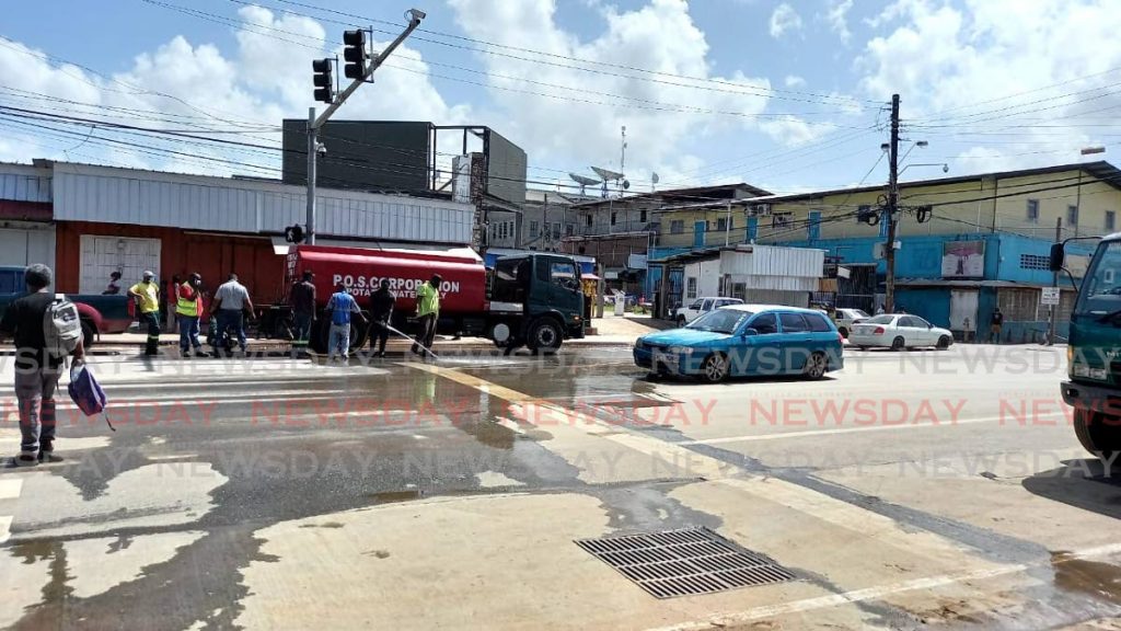 Several cleaning teams from the Port of Spain Corporation worked for hours to move the debris, garbage and mud left by the flooding on Tuesday. - Photo by Grevic Alvarado