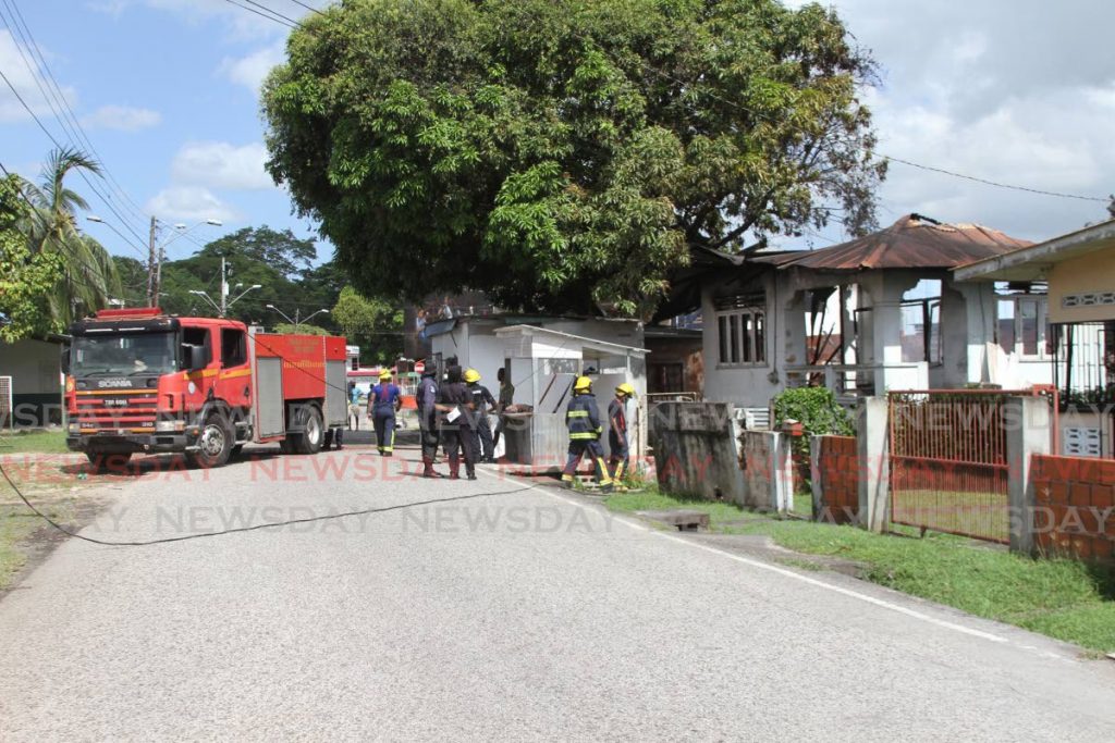 Fire officers at Clifford Street, St Augustine where a house was destroyed by fire on Wednesday. Photo by Marvin Hamilton.