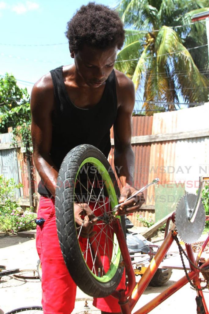 Trevon Farrier works on a bike at his home in Petit Bourg. - Photo by Marvin Hamilton