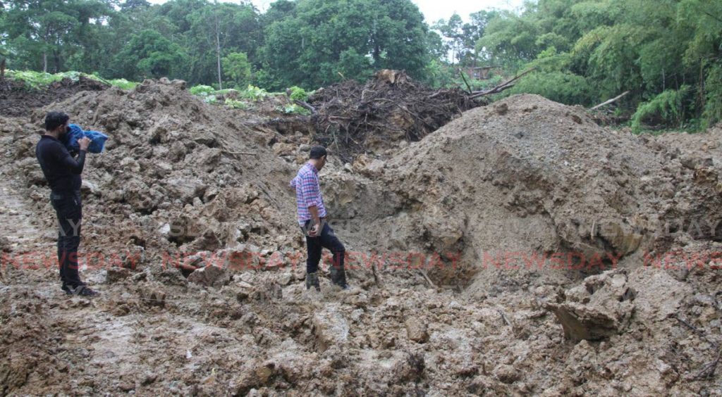 Media personnel look at the shallow grave from which the body of Annalisa Gokool was removed at Warden Road, Sangre Chiquito on Monday morning.  - Photo by Angelo Marcelle