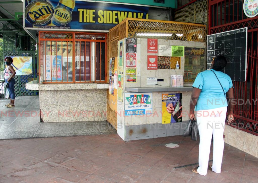 This lady looks at the Play Whe results at the Sidewalk Bar in Tunapuna. - Photo by Ayanna Kinsale