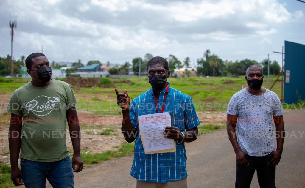 Wolwin Lovell, centre, and two other residents on Monday protest the plan to close the south entrance to Silk Cotton Trace before residents are compensated for their properties.   - DAVID REID 