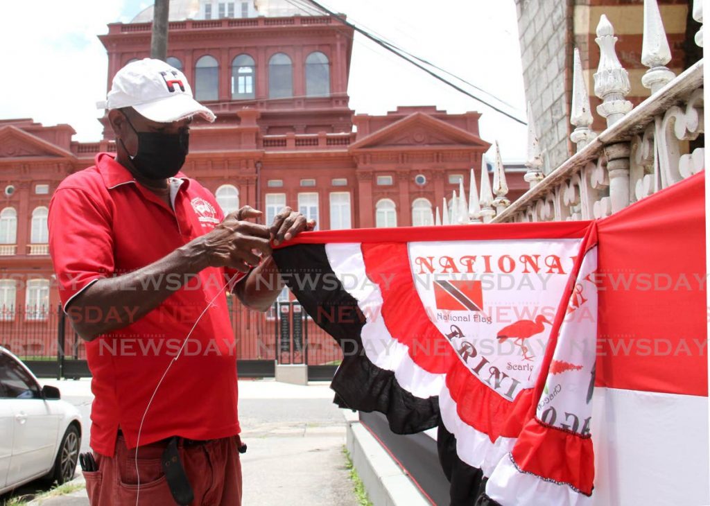Sheldon Kelly attaches decorations to commemorate TT's 59th anniversary of indepdendence to the Old Police Headquarters on Sackville Street, Port of Spain earlier this month. Independence Day is August 31.  

File photo/Ayanna Kinsale
