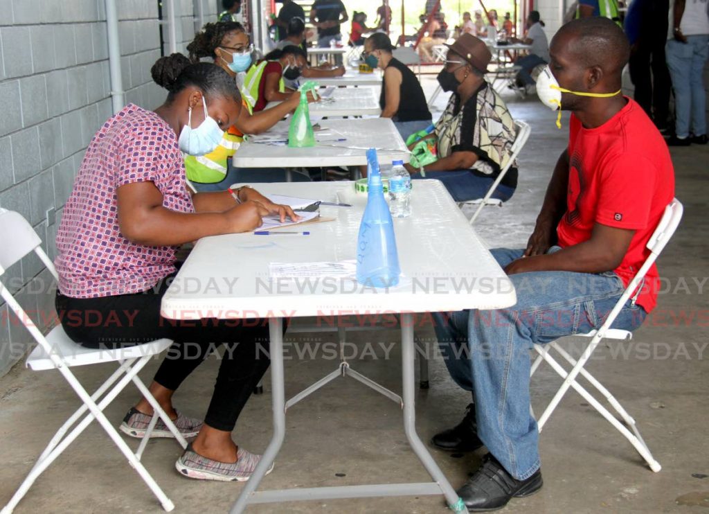 Volunteers register members of the public for vaccination at the Larry Gomes Stadium, Arima on Saturday. - PHOTO BY AYANNA KINSALE