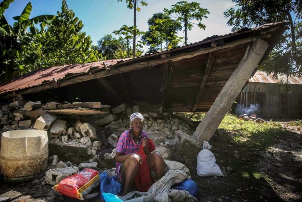 A woman sits in front of a destroyed house after the earthquake in Camp-Perrin, Les Cayes, Haiti, Sunday. AP PHOTO - 