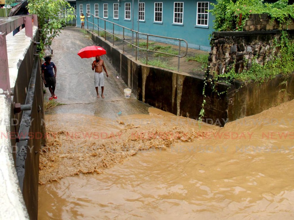 These men look at the flood water at East Dry River in Port of Spain.  - Photo by Ayanna Kinsale 
