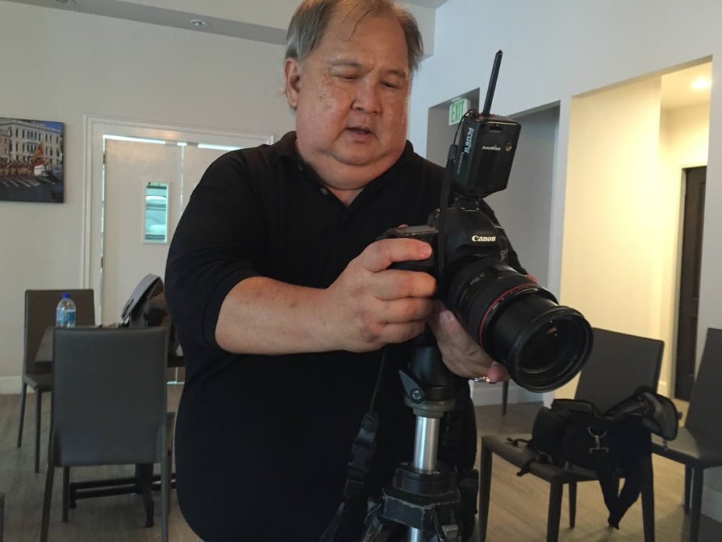 Russell “Butch” Limchoy makes an adjustment to his camera during a photoshoot. - PHOTO COURTESY SARITA RAMPERSAD