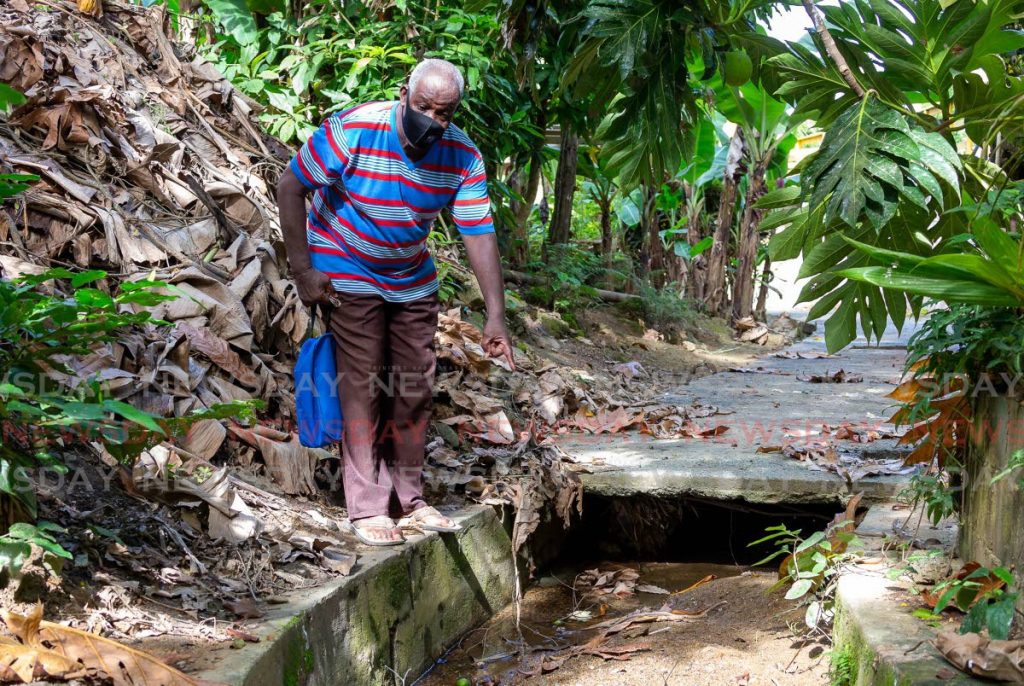 Bishop Innis Edwards shows a drain filled with silt and other debris at Depot Road, Castara, Tobago. Photo by David Reid