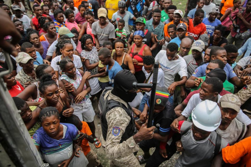 A police officer tries to bring order as earthquake victims scramble for a handout of rice at a food distribution place in Les Cayes, Haiti. AP Photo - Joseph Odelyn
