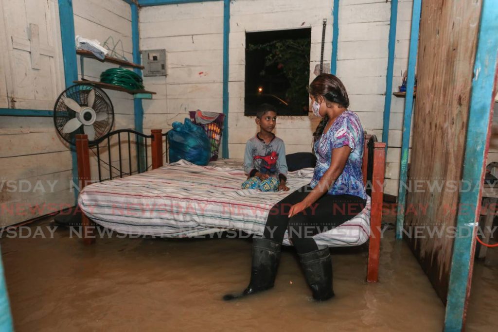 With nowhere else to turn, Kassandra Baboolal tries to comfort one of her two sons, Varendra  Roopchan, in their flooded home at Suchit Trace, Penal on Wednesday night.   - Jeff K. Mayers