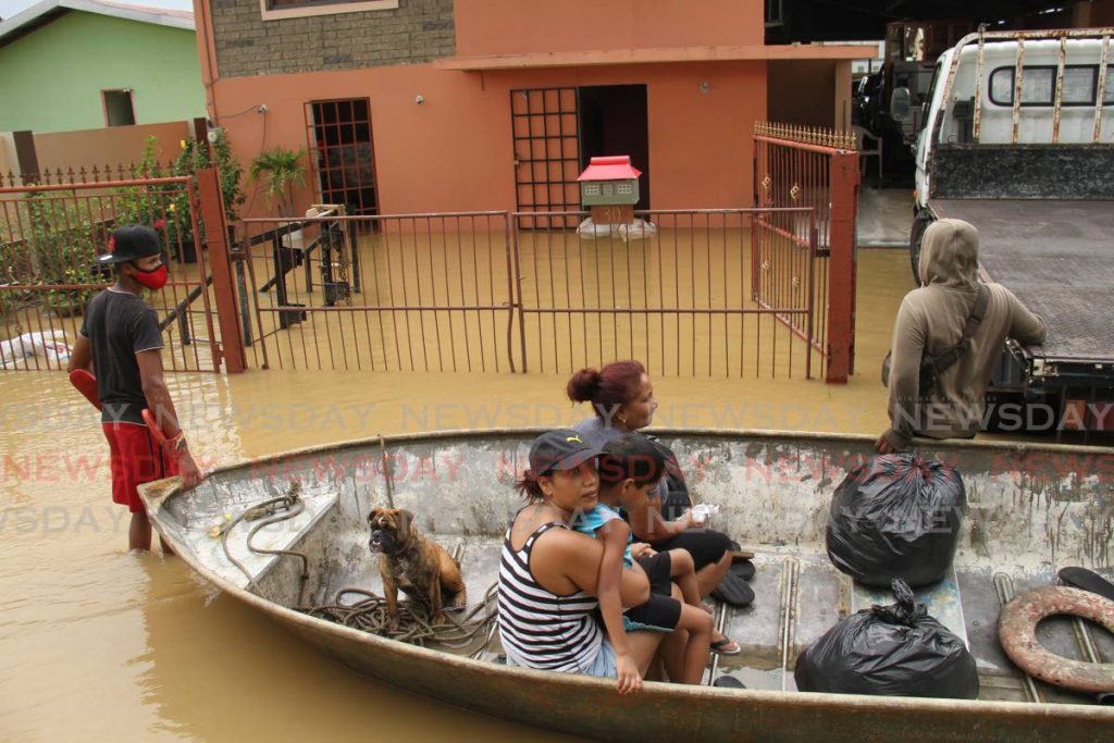 Madras Road, St Helena residents use a boat to make their way to safety after their homes were flooded on Thursday. - Ayanna Kinsale