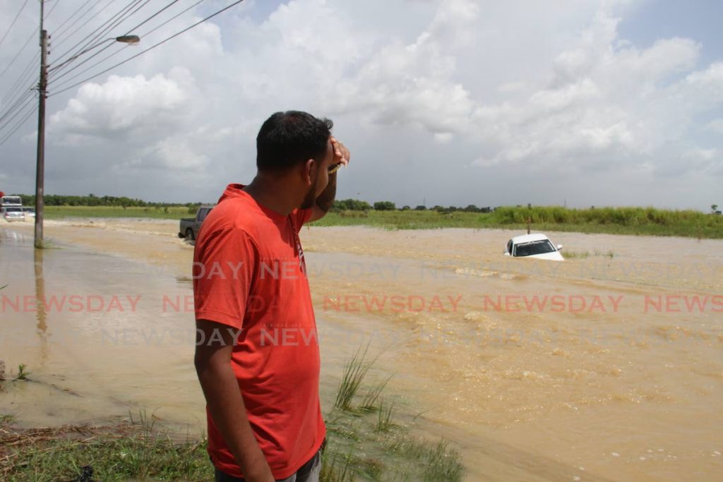 Sadeek Razack looks at his car as it remained in the flood waters along the St Helena Bypass Road in Kelly Village, Caroni on Thursday. - Ayanna Kinsale