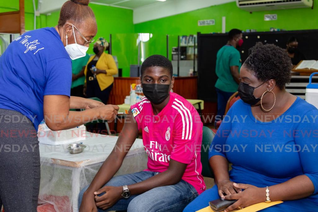 Signal Hill Secondary student Darion James, centre, receives his Pfizer vaccine as his mother Rachel James observes at the Tobago school on Friday. - Photo by David Reid