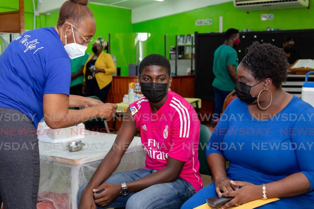 Signal Hill Secondary student Darion James, centre, receives his Pfizer vaccine as his mother Rachel James observes at Signal Hill Secondary School on Friday. PHOTO BY DAVID REID  - 