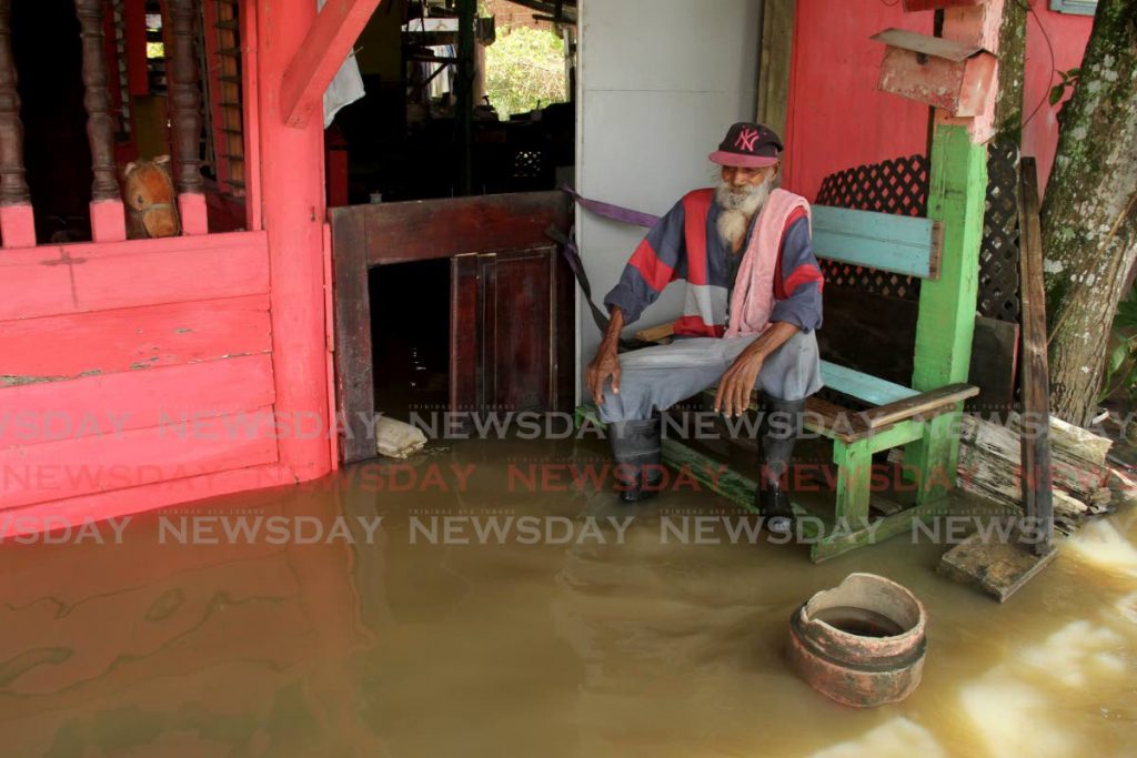 Basdeo Maraj looks on as floodwater settles around his home in Chris Avenue, St Helena on August 20, after rivers overflowed following days of heavy rainfall. - PHOTO BY AYANNA KINSALE