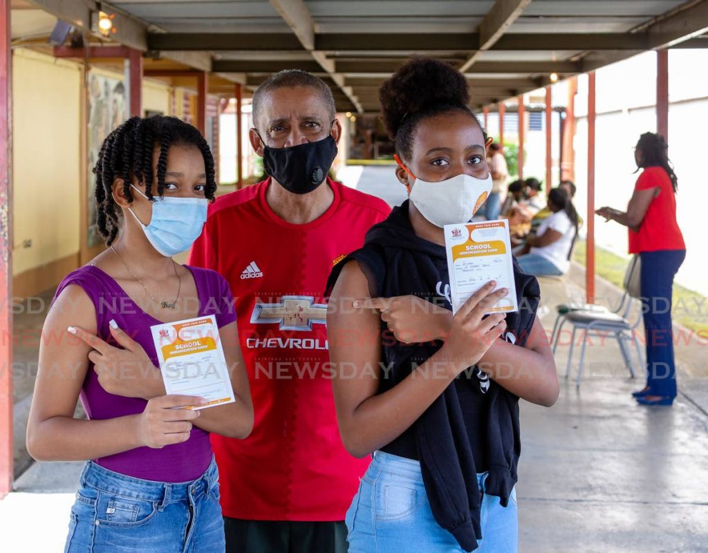 Tonya Wilson, 14, left and her best friend A'niah Taitt, 14, show their vaccination cards after receiving the Pfizer covid19 vaccine on Friday at Signal Hill Secondary School in Tobago. Present to supervise was Tonya's father Nigel Wilson. - Photo by David Reid