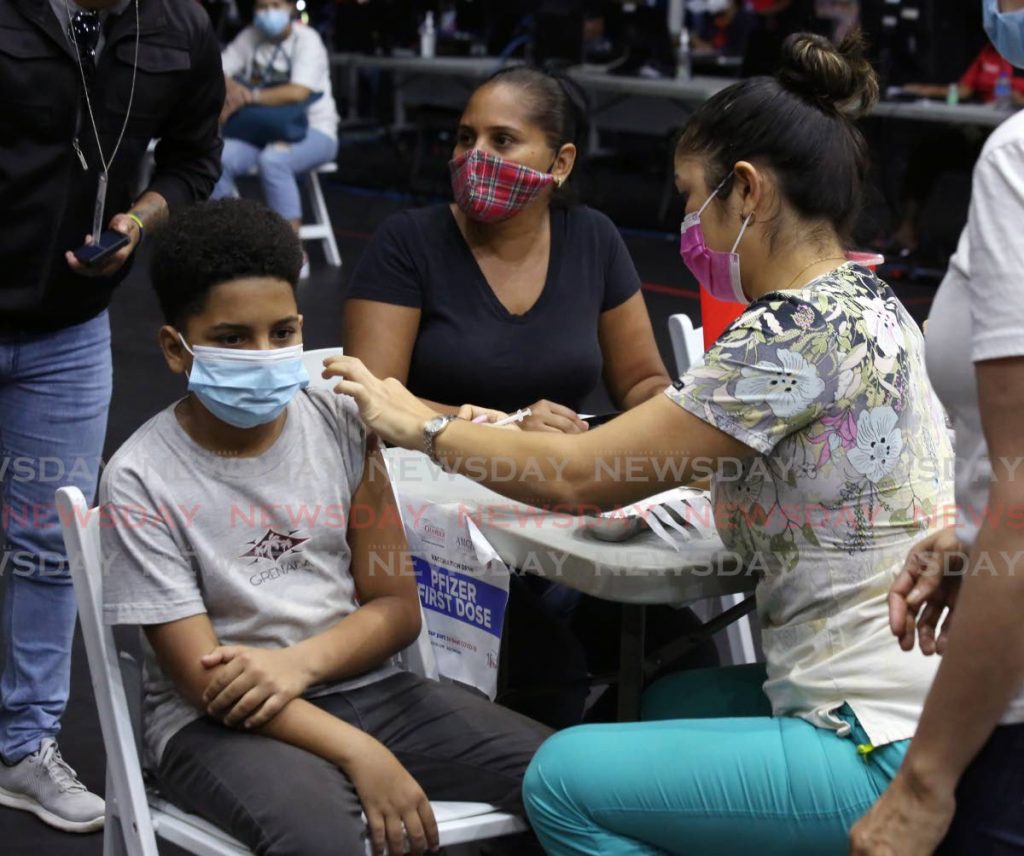 Adrian Leon, 12, receives the Pfizer covid19 vaccine, with his mother Jorcna Osorio, centre, at his side at the National Academy for the Performing Arts, Port of Spain on Saturday. - Photo by Sureash Cholai