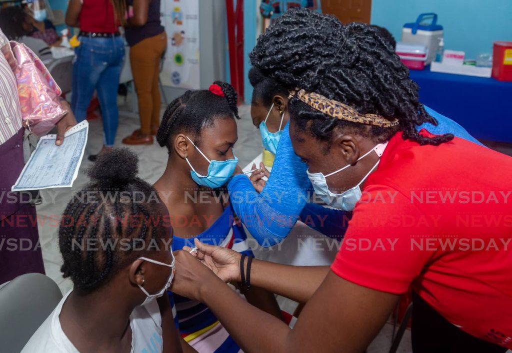 Cousins Unique Destin, 13, right, and Anastasia Gibbs, 12, get their Pfizer covid19 vaccines, supervised by their grandmother Marva Pierre at Scarborough Secondary School on Monday. - Photo by David Reid