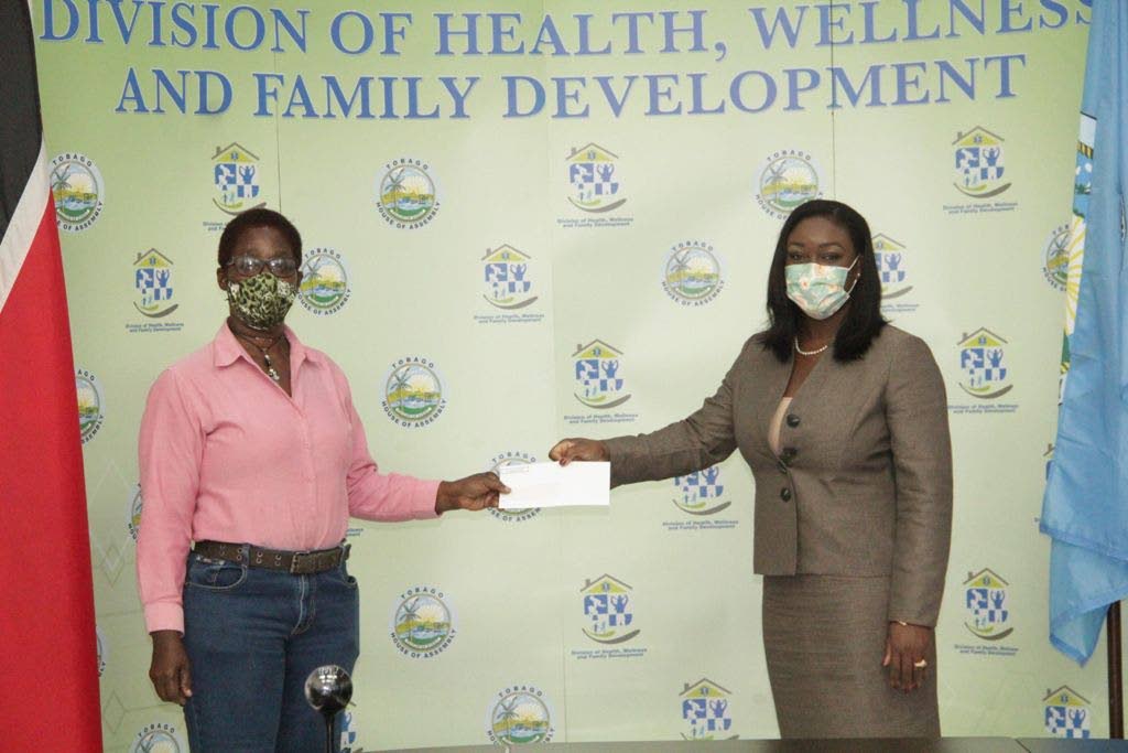 Secretary of Health, Wellness and Family Development Tracy Davidson-Celestine, right, hands a cheque to landlord Althea Gordon at a distribution ceremony for the rental assistance grant. - 
