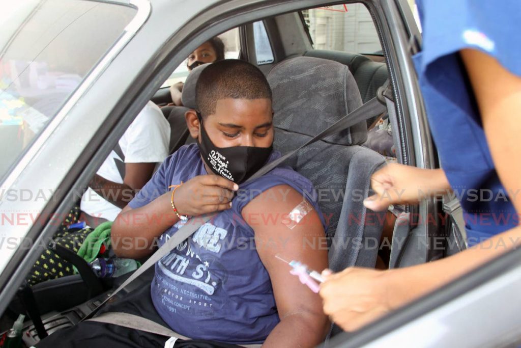 Nicholas Charles, 13, who attends the Couva West Secondary School receives his first dose of the Pfizer vaccine at the Ato Boldon Stadium, Couva, on Thursday. - Lincoln Holder