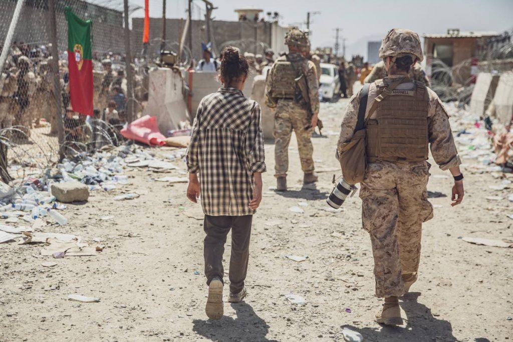In this image provided by the US Marine Corps, a Marine with Special Purpose Marine Air-Ground Task Force - Crisis Response - Central Command, escorts a young girl at an evacuation control checkpoint during an evacuation at Hamid Karzai International Airport in Kabul, Afghanistan, on August 26, 2021.  - 