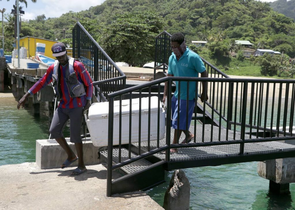 Fishermen carry a cooler along the steel stairway bridging the damaged Parlatuvier jetty.  - DIQE