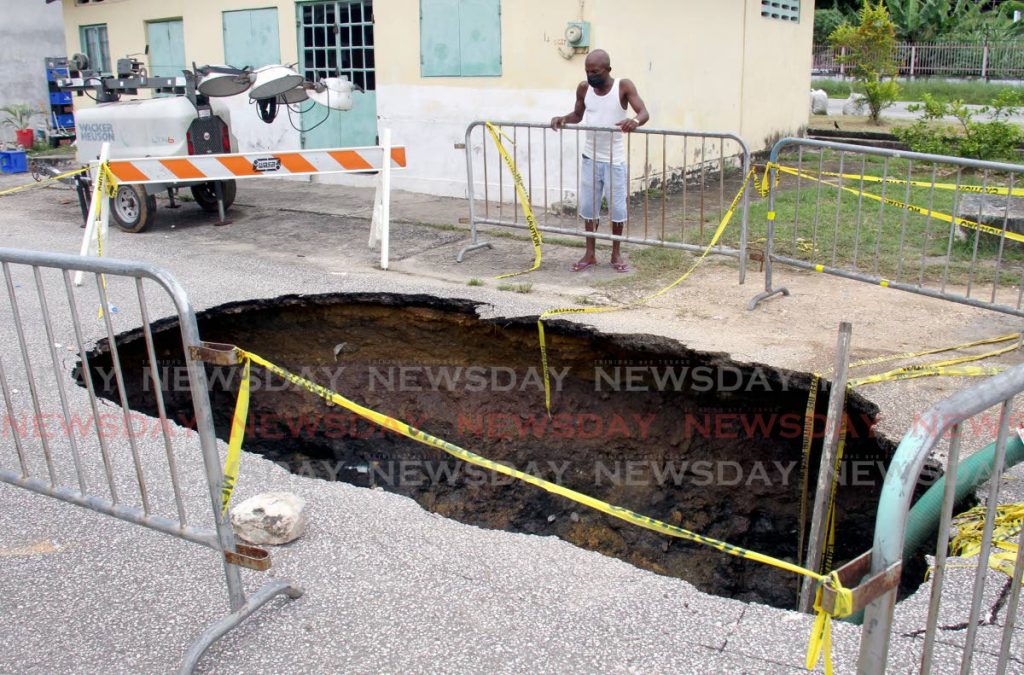 Anderson Wilson looks at the sinkhole at Main Street, Beetham Gardens which appeared when a sewer line ruptured. - Ayanna Kinsale