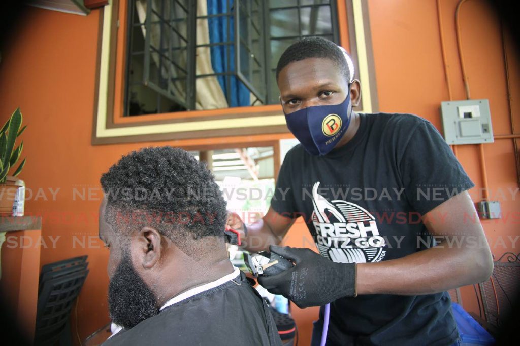 Owie Bowen of Sobo Village, La Brea, cuts a customer's hair at his barbershop. Photo by Lincoln Holder - Lincoln Holder