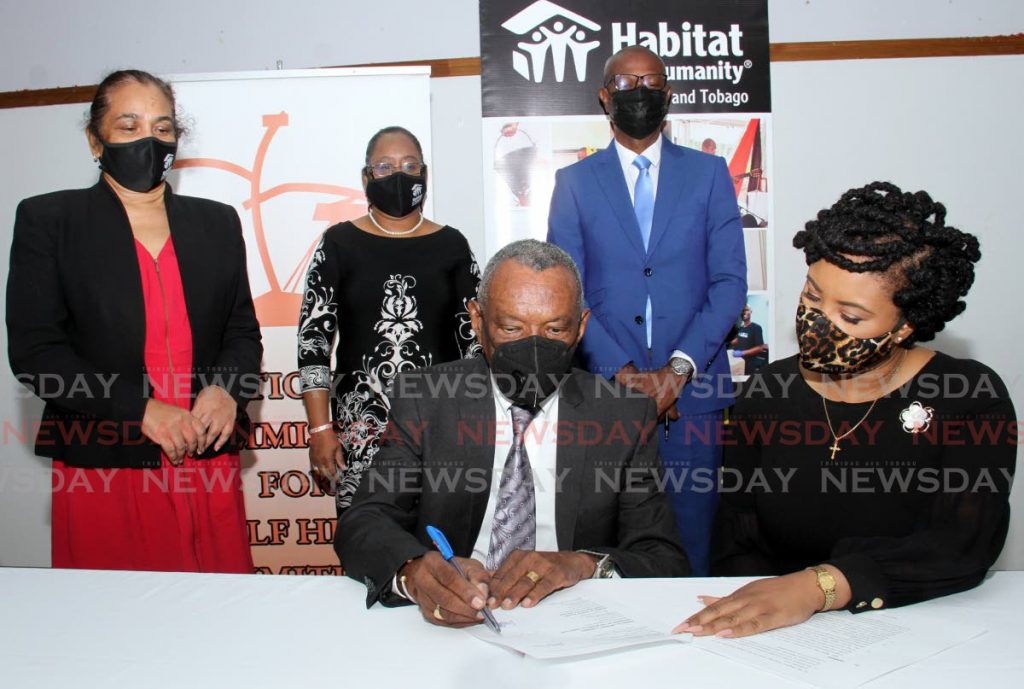 at right, the honorable Shamfa Cudjoe, Minister of Sport and Community Development looks to Anthony Campbell, Chairman of the National Commission for Self Help, as he signs the Memorandum of Agreement between National Commission for Self Help and Habitat for Humanity at the Mt. Lambert Community Centre on Community Drive in San Juan.
(standing behind from left)Officals from Habitat for Humanity Trinidad and Tobago; Resource Development Coordinator Carlene Pooran and National Director Jennifer Massiah, alongside Elroy Julien CEO of the Self Help Commission. - AYANNA KINSALE