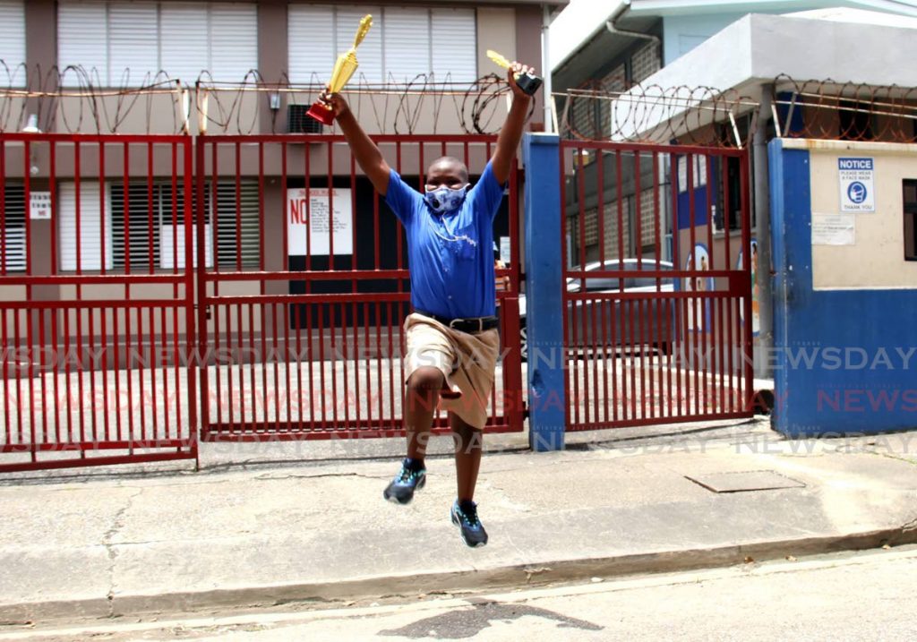 Top SEA student of Nelson Street Boys RC School Trey Jones leaps for joy as he holds his trophies after receiving his exam results. Photo by Ayanna Kinsale - Ayanna Kinsale