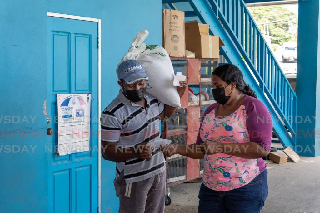 Davila Boodram, right, drove from Speyside village to buy starter feed for her chickens and dog rice from Mt Grace Feed Depot Ltd, Mt Grace, Tobago on Saturday. Scarborough/Mt Grace is one of the 15 electoral districts proposed in the EBC Order. - PHOTO BY DAVID REID