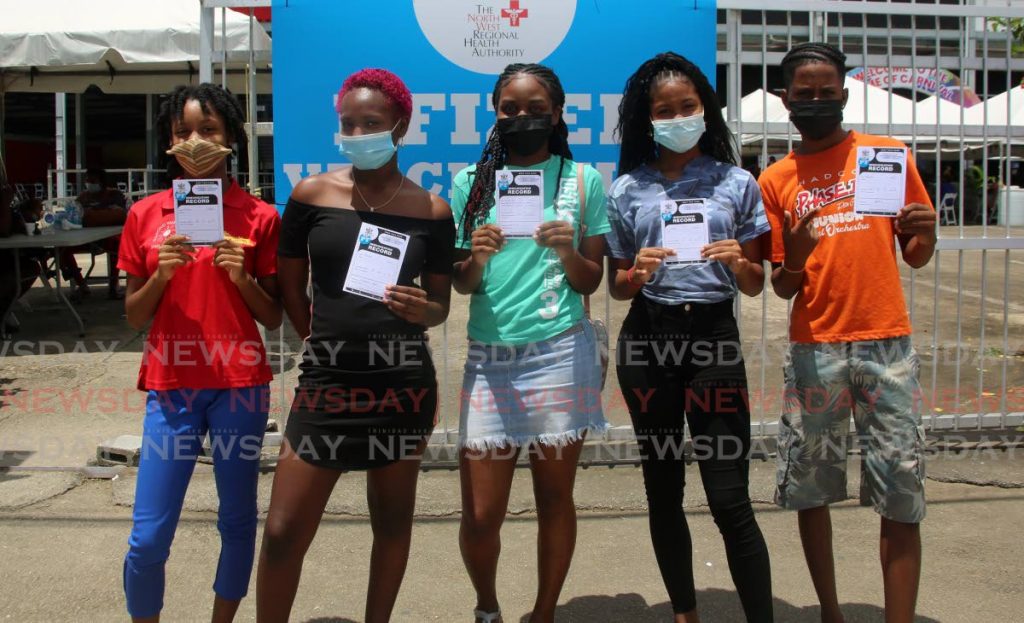 Secondary school students hold their vaccination cards after receiving the Pfizer vaccine at the Paddock, Queen's Park Savannah Port of Spain on September 13. - Photo by Sureash Cholai