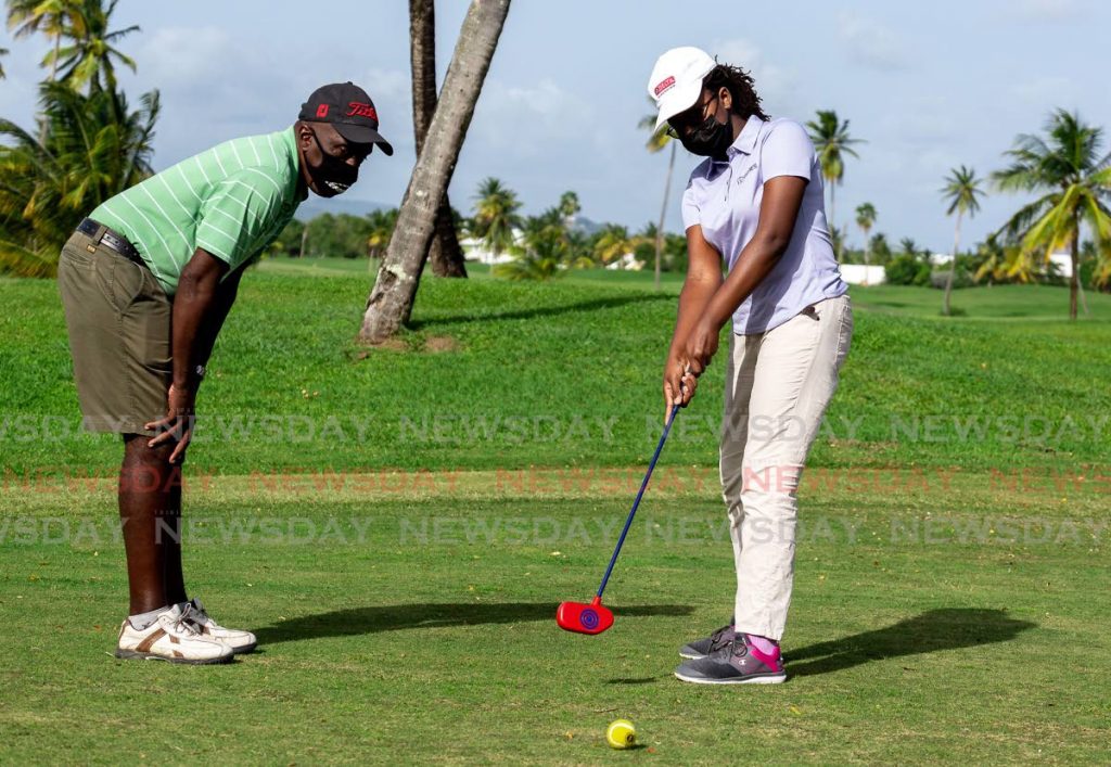 Golf coach Ricky Campbell, left, helps one of his students with her putting technique at the Magdalena Grand Beach and Golf Resort.   - Photo by David Reid