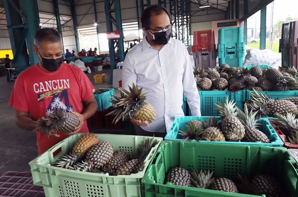 In this file photo, Agriculture Minister Clarence Rambharat, left, and Chaguanas West MP Dinesh Rambally observe pineapples at a stall during their tour of the Woodford Lodge wholesale market in Chaguanas. The agriculture sector has been allocated $1.249 billion for the fiscal 2022 budget.