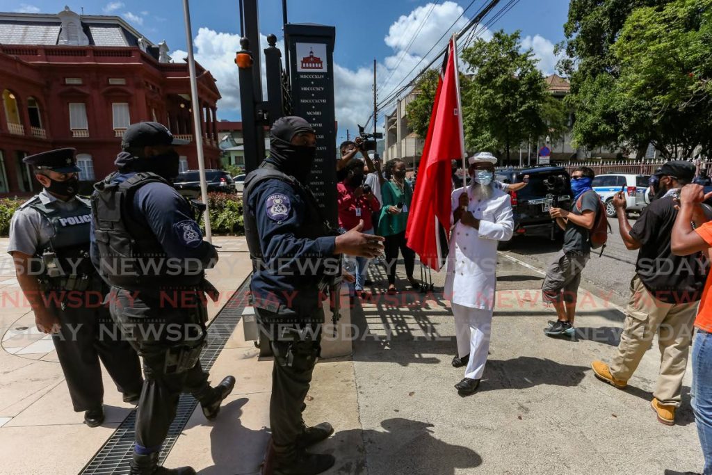 In this August 25 file photo, activist Umar Abdullah was cautioned by police to leave the entrance of the Red House, where the Prime Minister Keith Rowley led the debate to extend the SoE by another three months. Photo by Jeff Mayers