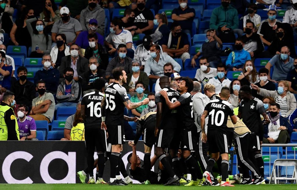 Sheriff’s Sebastien Thill celebrates with teammates after scoring his side’s second goal during the Champions League group D match against Real Madrid at the Bernabeu stadium in Madrid, Spain, on Tuesday.  At left, wearing No 16, is Trinidad and Tobago's Keston Julien. - AP PHOTO